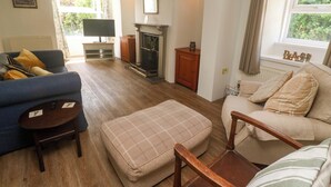 Una sala de estar con chimenea, un sofá, un sillón y un televisor.
