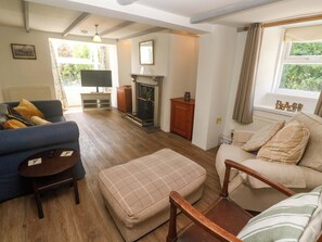 A living room with a fireplace, a sofa, a chair, and a television. - Greenways (Perranporth)