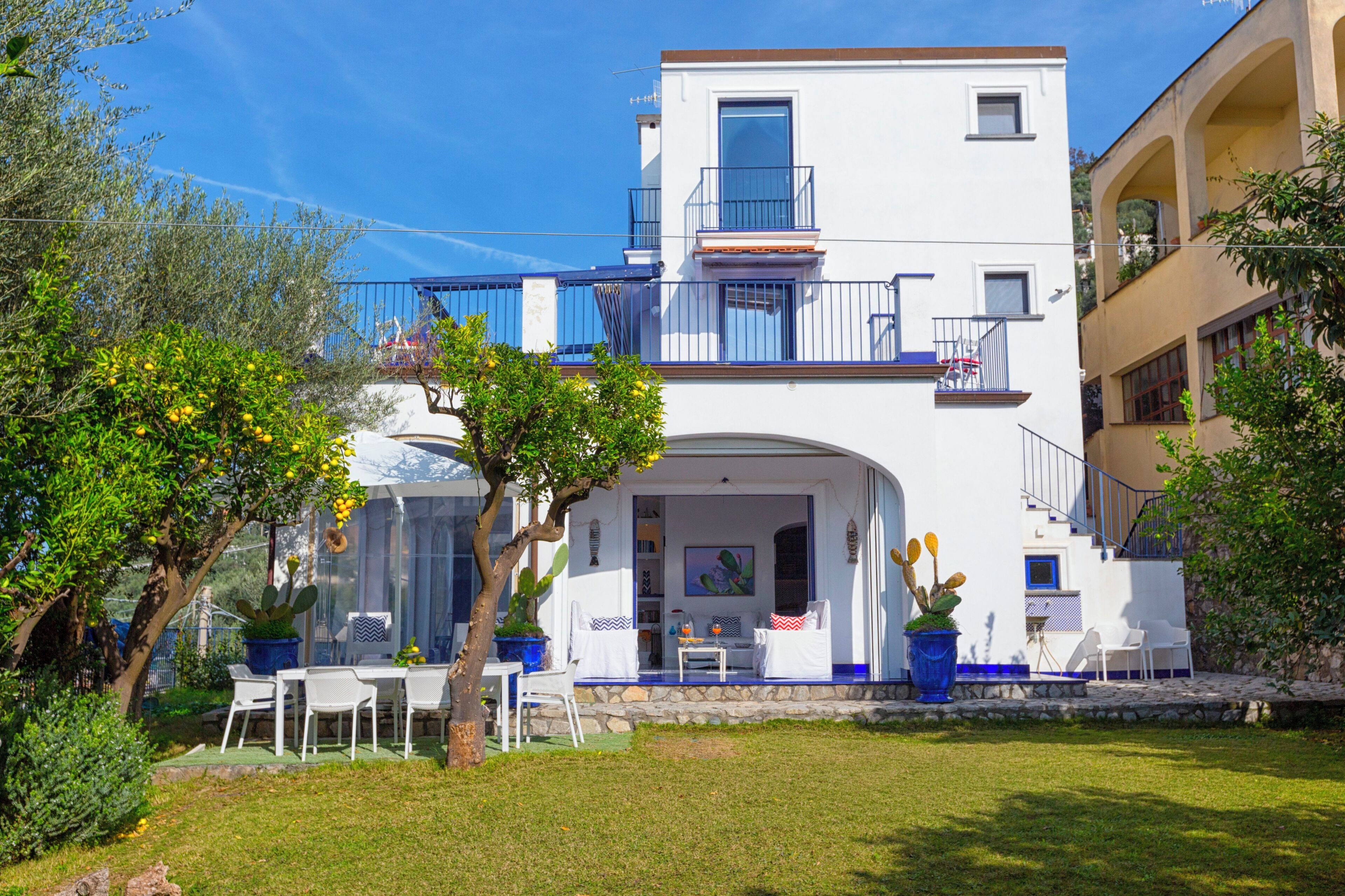 A two-story building with a balcony, outdoor seating area, and a garden.
