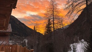 Eine Hütte mit Blick auf ein bewaldetes Tal und einen Sonnenuntergang.