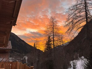 Eine Hütte mit Blick auf ein bewaldetes Tal und einen Sonnenuntergang.