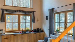 Eine kleine Küche mit Holzschränken, einer eingebauten Spüle und einem Essbereich mit einer Couch und Stühlen.