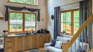 Eine kleine Küche mit Holzausstattung, einem eingebauten Herd und einem Essbereich mit Sofa und Tisch.