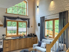 Eine kleine Küche mit Holzausstattung, einem eingebauten Herd und einem Essbereich mit Sofa und Tisch.