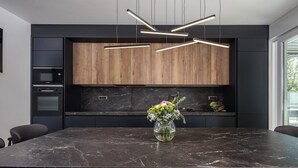 Een moderne keuken met een marmeren aanrechtblad, houten kastjes en een bloemenvaas.