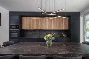 Eine moderne Küche mit Marmorarbeitsplatte, Holzschränken und einem Blumenstrauß.