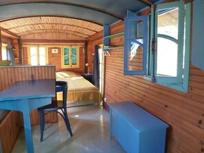 Een kamer met een bed, een bureau, een stoel en een raam met luiken.