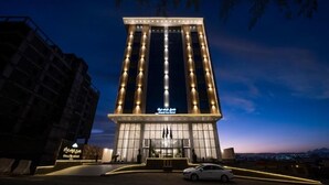 Un hotel alto de diseño moderno, con una entrada destacada y una fachada bien iluminada.