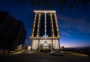 Un hotel alto de diseño moderno, con una entrada destacada y una fachada bien iluminada.