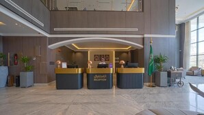 A reception area with three counters, a flag, and a seating area. - Grand Iva Hotel Abha (Abha)