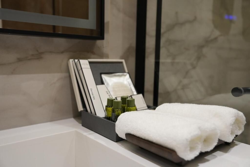 A bathroom with a white bathtub, a towel, and a tray with toiletries.