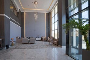 Un vestíbulo amplio con techos altos, mobiliario moderno y ventanas grandes.