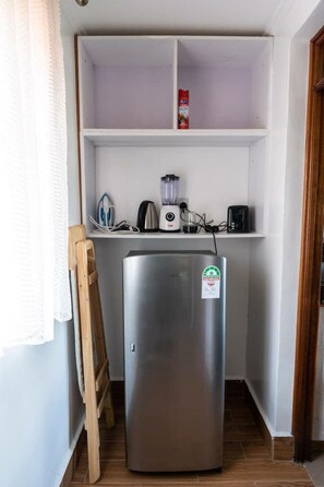 Eine kompakte Küche mit Edelstahl-Kühlschrank, Wasserkocher, Toaster und Mixer auf der Arbeitsfläche.
