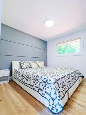 Ein Schlafzimmer mit einem Bett, einem Nachttisch, einem Fenster und einer Deckenleuchte.