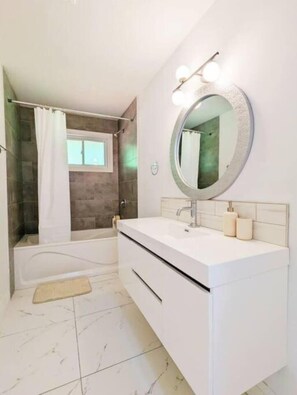 Une salle de bain moderne avec une baignoire, un grand miroir et un meuble-lavabo.