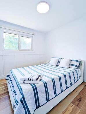 Une chambre à coucher avec un lit, une fenêtre et un luminaire au plafond.