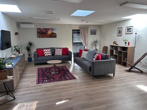 Ein modernes Wohnzimmer mit grauem Sofa, Couchtisch, Fernseher und Bücherregal.