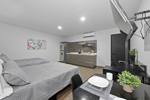 A modern hotel room with two beds, a kitchenette, a dining area, and a painting on the wall. - Loft Moderno con 2 Queen Beds Zona Tec  loft 17 (Monterrey)