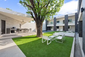 A modern outdoor area with a pool, seating, and a large tree. - Loft Moderno con 2 Queen Beds Zona Tec  loft 17 (Monterrey)