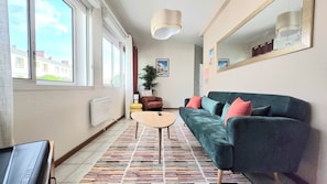 Ein modernes Wohnzimmer mit einer Couch, einem kleinen Tisch, einem Heizkörper und einem großen Fenster.