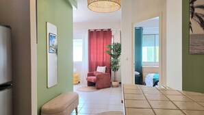 Un couloir avec un banc, une chaise, une plante et un lit en arrière-plan.