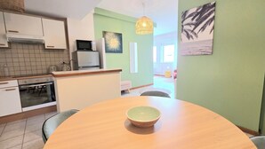 Une cuisine moderne équipée d’un four à micro-ondes, d’une cuisinière et d’un évier. On y trouve une table à manger avec un saladier au centre.