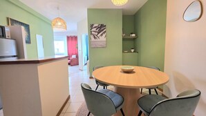 Un coin repas comprenant une table ronde, quatre chaises, un saladier et un luminaire suspendu.