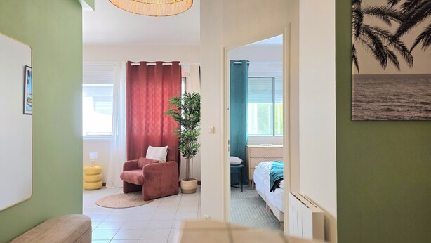 Une chambre avec un lit, une chaise, une plante et une vue sur la mer.