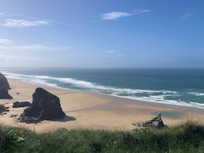 A beach with clear skies, waves, and rocky formations. - Garden Lodge: your perfect base for exploring Cornwall (Bodmin)