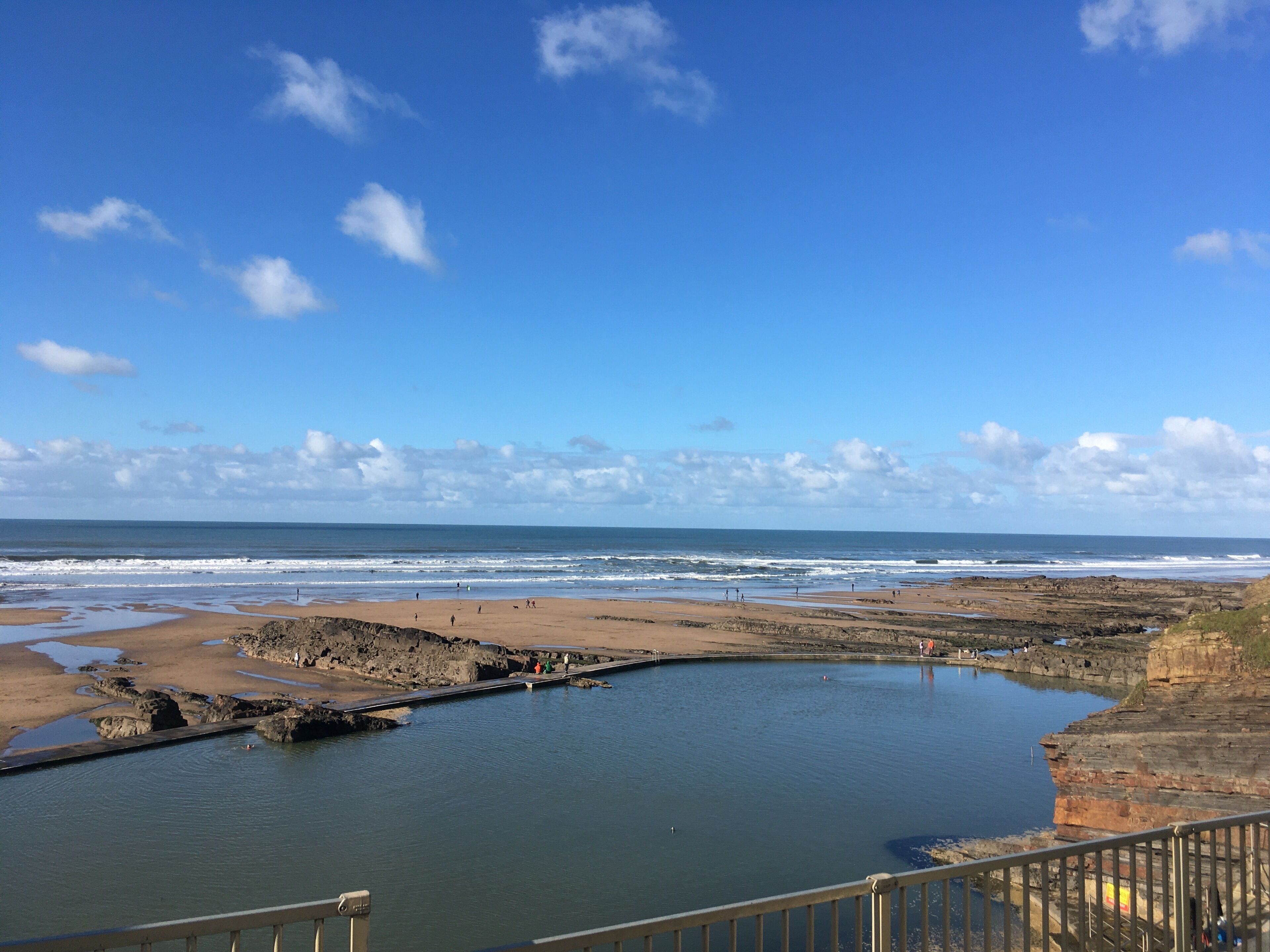 Eine Küstenlandschaft mit Strand, felsigem Gelände und ruhigem Gewässer.