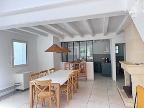 A dining area with a table and chairs, a kitchen in the background, and a fireplace. - Vrbo Property (Saint-Pierre-d'Oléron)