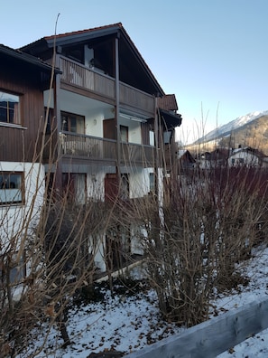Un bâtiment à deux étages doté d’un balcon, d’une façade en bois et offrant une vue sur une montagne enneigée.