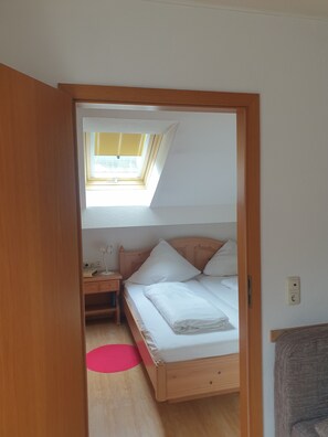 Une chambre avec un puits de lumière, un lit, une table de chevet et un bureau.