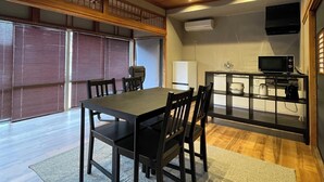 Un espace repas avec une table et des chaises, un coin cuisine équipé d’appareils électroménagers et une vue par la fenêtre.