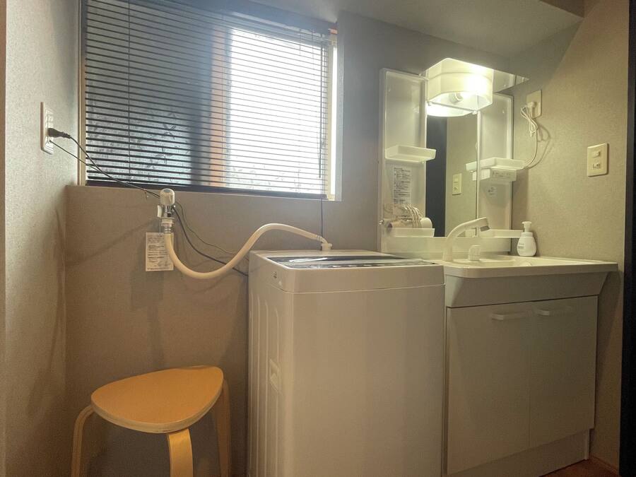 Un baño pequeño con lavadora, lavamanos e inodoro.