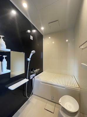 Casa de banho moderna com chuveiro, sanita e prateleira com produtos de higiene pessoal.