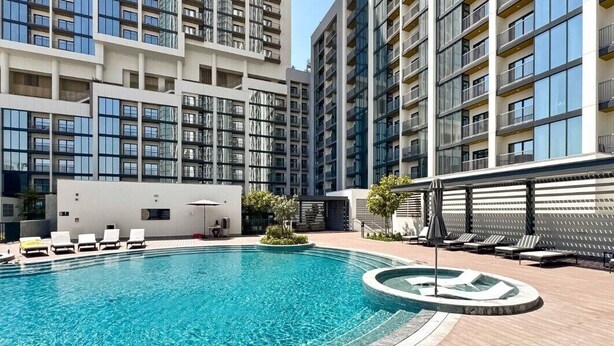Ein modernes Apartmenthaus mit Schwimmbad, Liegestühlen und Sonnenterrasse.