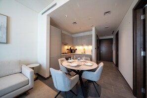 A modern kitchen with a dining area, a sofa, and a small side table. - Premium 1BR Plus Study Canal View Near Downtown (Dubai)