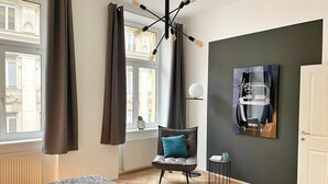 A modern hotel room with a bed, a chair, a table, and a painting on the wall. - Exceptional design loft directly on Mariahilfer Strasse i (Vienna)