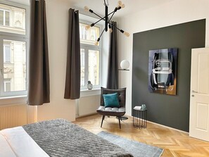 Ein modernes Hotelzimmer mit einem Bett, einem Sessel, einem Tisch und einem Bild an der Wand.