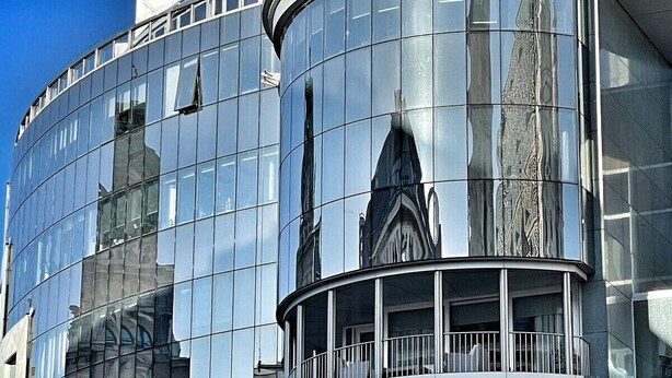 A modern building with curved glass facades and a balcony. - Exceptional design loft directly on Mariahilfer Strasse i (Vienna)