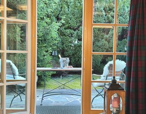 Ein Zimmer mit einem großen Fenster, einem Tisch mit Eimer und Erdbeeren und einem Stuhl mit einer weißen Federdekoration.