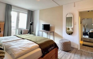 Une chambre d’hôtel avec un lit, une télévision, un miroir et un petit tabouret.