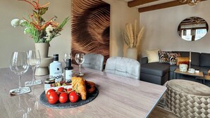 Uma sala de jantar moderna com uma mesa de mármore, copos de vinho, azeite e um croissant.