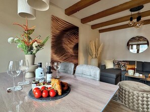 A modern dining area with a marble table, wine glasses, olive oil, and a croissant. - Stylish design apartment for 3-4 people in the heart of Kitzbühel (Kitzbühel)