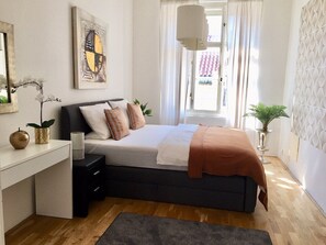 A bedroom with a bed, bedside table, lamp, and a window with curtains. - Style & Design No. 1 City Centre Prag Style & Design No. 1 City Centre Prag (Praha 1)