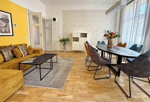 Ein modernes Wohnzimmer mit Sofa, Couchtisch und Essbereich mit Stühlen und einem Tisch.