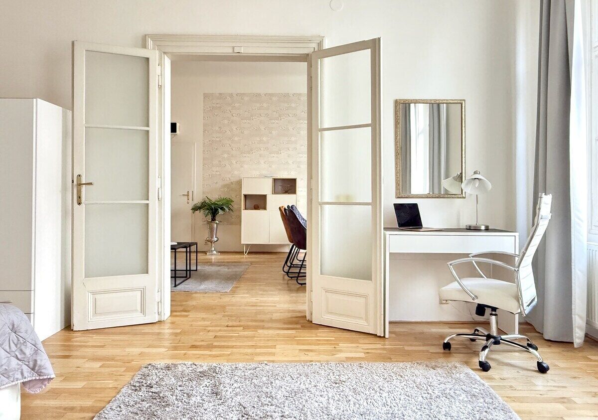A room with a desk, chair, open door, and a plant.