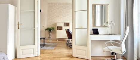 A room with a desk, chair, open door, and a plant.