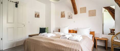 Un dormitorio con una cama, una silla de madera, una mesita de noche y un espejo.
